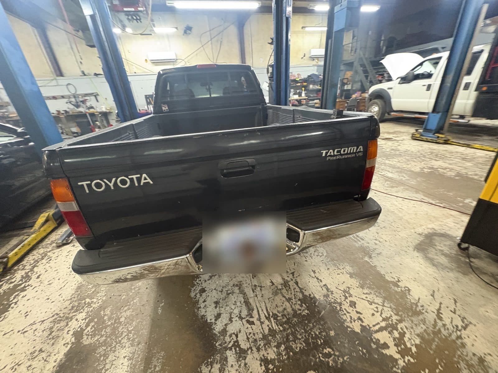 Black 1999 Toyota Tacoma PreRunner V6 in a bay at Zoom Automotive in Lynchburg, license plate blurred